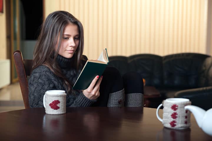 woman sitting at a table reading interesting book
